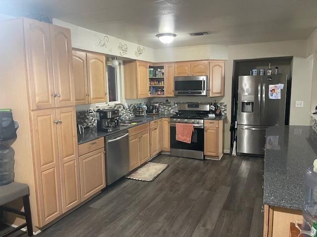 kitchen featuring sink, dark stone counters, dark wood-type flooring, and stainless steel appliances