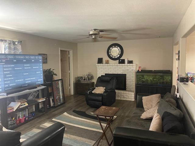 living room with ceiling fan, hardwood / wood-style floors, and a brick fireplace