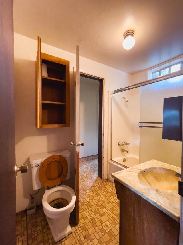 full bathroom with combined bath / shower with glass door, toilet, tile patterned floors, and vanity