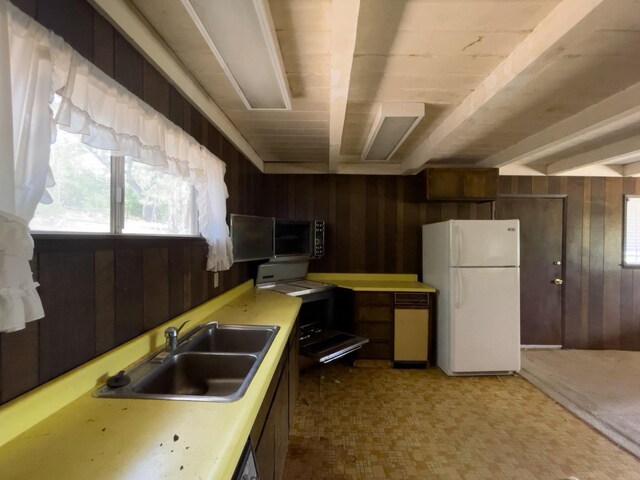 kitchen with sink, wooden walls, white refrigerator, and beam ceiling