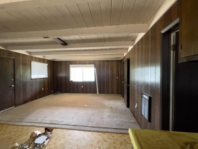 empty room featuring beam ceiling and wooden walls