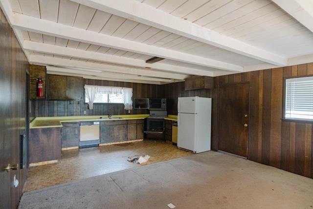 kitchen with beam ceiling, dark brown cabinetry, sink, wooden walls, and white appliances