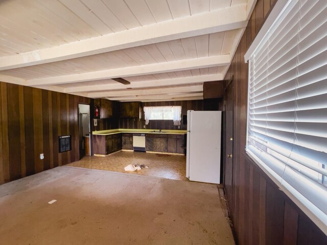 kitchen with wood walls, white appliances, sink, and beam ceiling