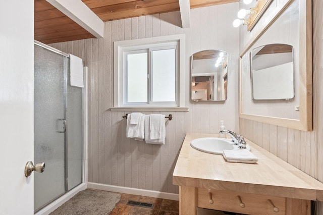 bathroom with wooden walls, vanity, and walk in shower