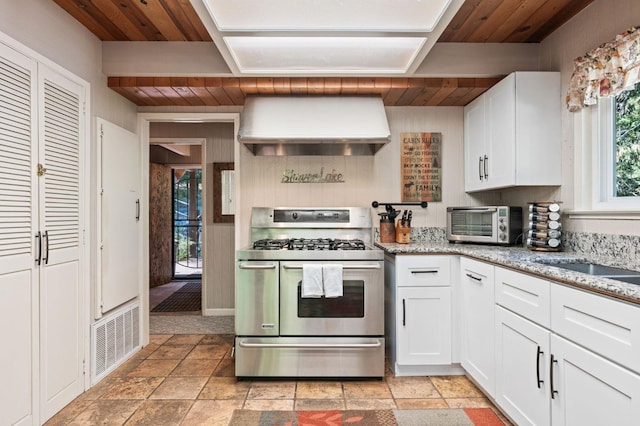 kitchen featuring range with two ovens, custom exhaust hood, white cabinets, wooden ceiling, and light tile patterned flooring