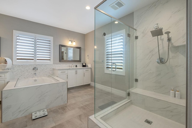 bathroom with independent shower and bath, a wealth of natural light, and vanity