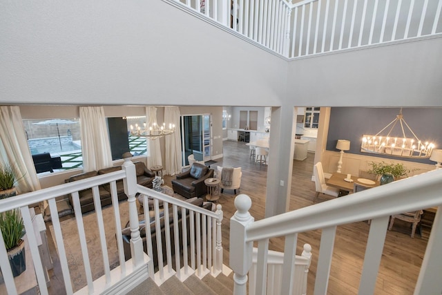 stairs with hardwood / wood-style floors, plenty of natural light, and a notable chandelier