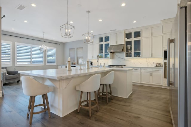 kitchen featuring hardwood / wood-style floors, white cabinetry, a spacious island, a chandelier, and appliances with stainless steel finishes