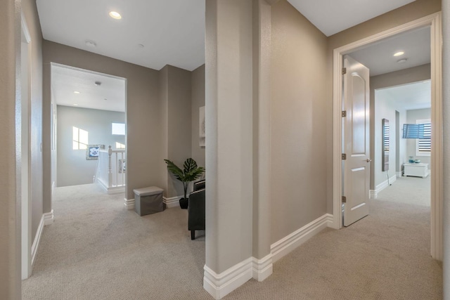 hallway with light carpet and a healthy amount of sunlight