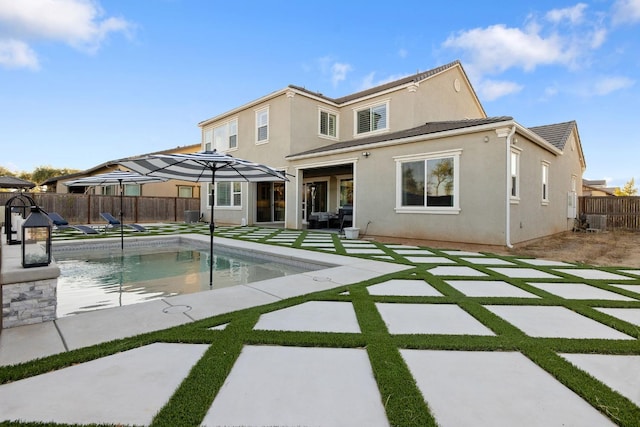 rear view of property with a fenced in pool and a patio