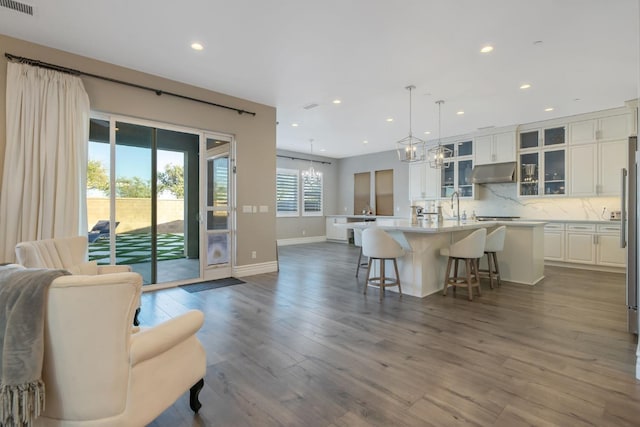 kitchen with a breakfast bar area, a notable chandelier, wood-type flooring, an island with sink, and hanging light fixtures