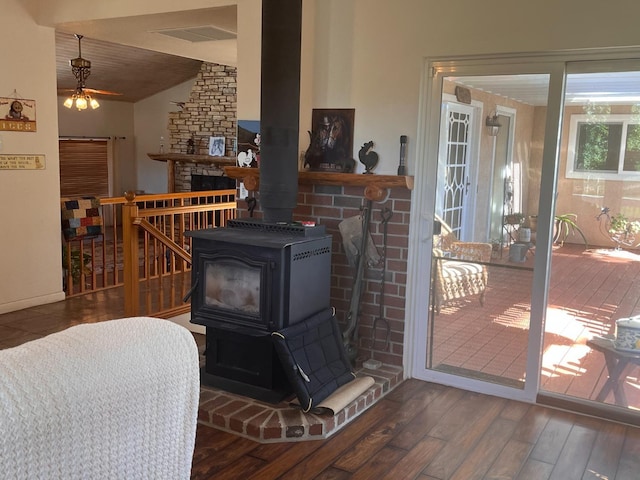 living room with vaulted ceiling, dark hardwood / wood-style flooring, ceiling fan, and a wood stove