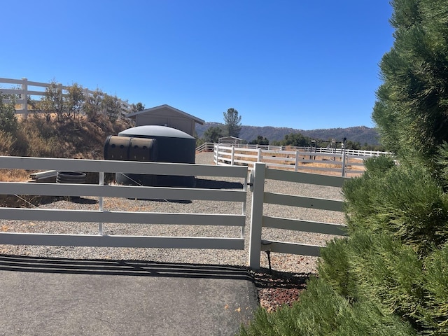 view of gate featuring an outbuilding, a rural view, and a mountain view