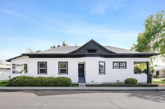 view of front facade featuring a shingled roof, entry steps, crawl space, and stucco siding