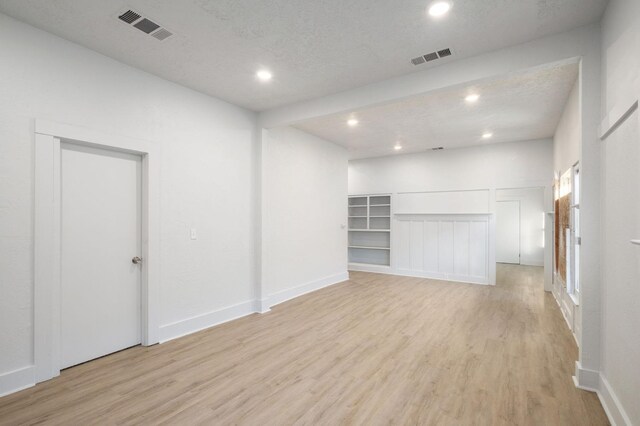 spare room featuring a textured ceiling and light hardwood / wood-style floors