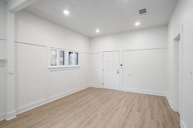 empty room featuring a textured ceiling and light hardwood / wood-style flooring