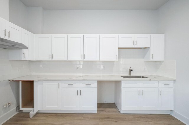 kitchen featuring light wood-type flooring, white cabinets, a sink, and under cabinet range hood