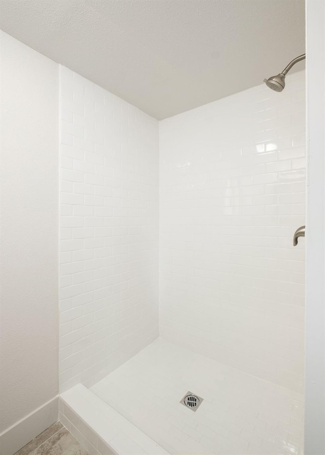 bathroom with a textured ceiling and tiled shower