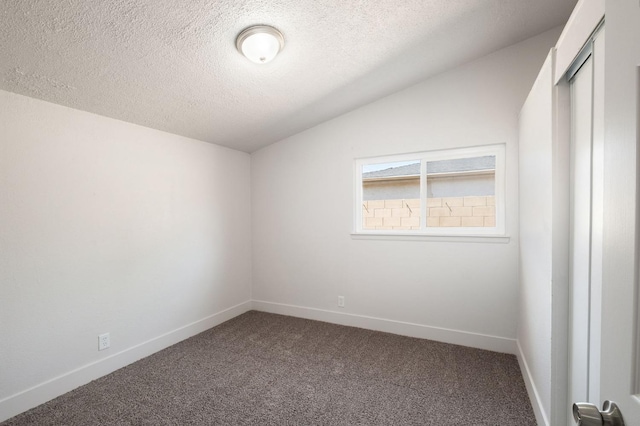 carpeted empty room with vaulted ceiling and a textured ceiling