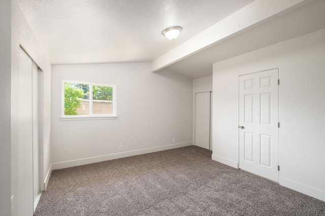 unfurnished bedroom featuring lofted ceiling with beams and carpet floors