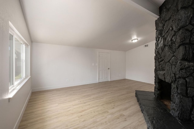 living room featuring light hardwood / wood-style floors, lofted ceiling, and a fireplace