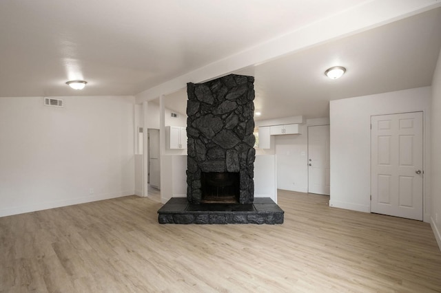 unfurnished living room featuring light hardwood / wood-style floors, a stone fireplace, and lofted ceiling