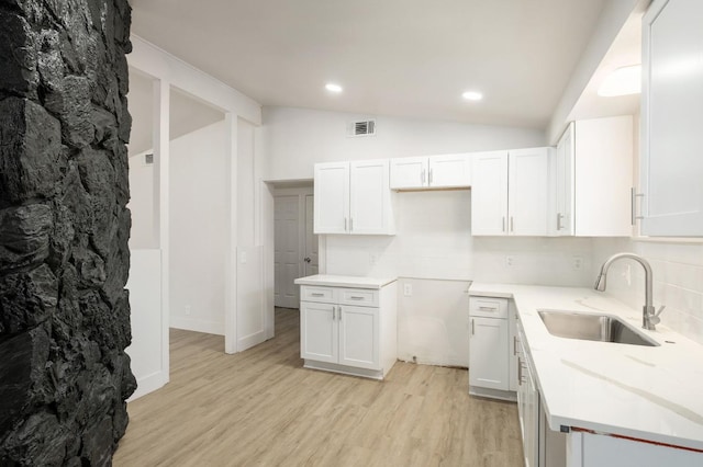 kitchen featuring backsplash, sink, light wood-type flooring, vaulted ceiling, and white cabinets