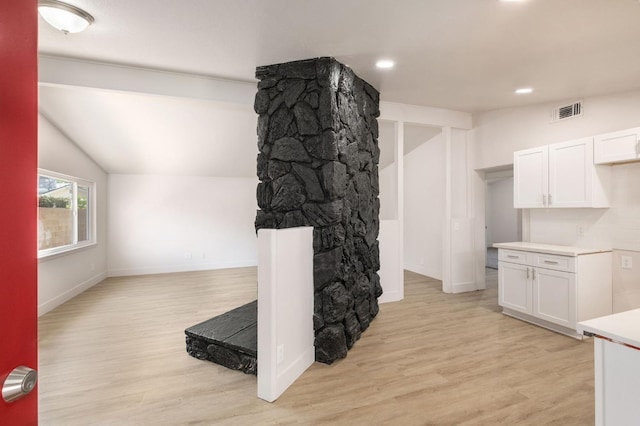 kitchen featuring light wood-type flooring, white cabinetry, and lofted ceiling