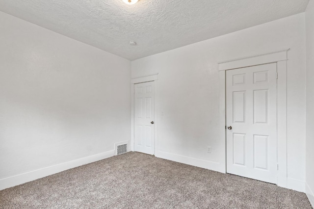 carpeted empty room featuring a textured ceiling