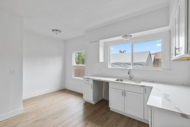 kitchen with decorative backsplash, light wood-type flooring, white cabinetry, and sink