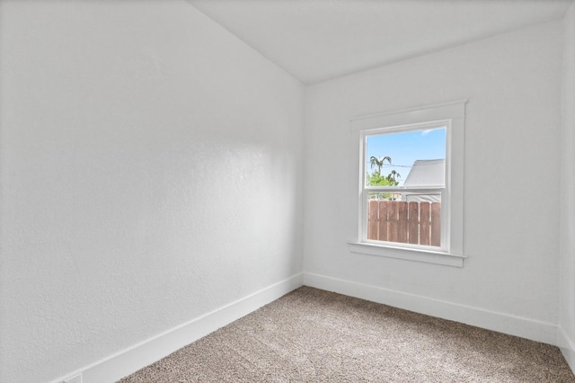 carpeted empty room featuring vaulted ceiling