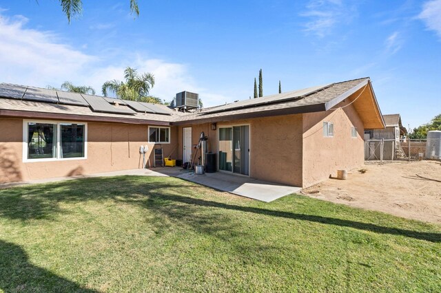 back of house featuring cooling unit, solar panels, a lawn, and a patio area