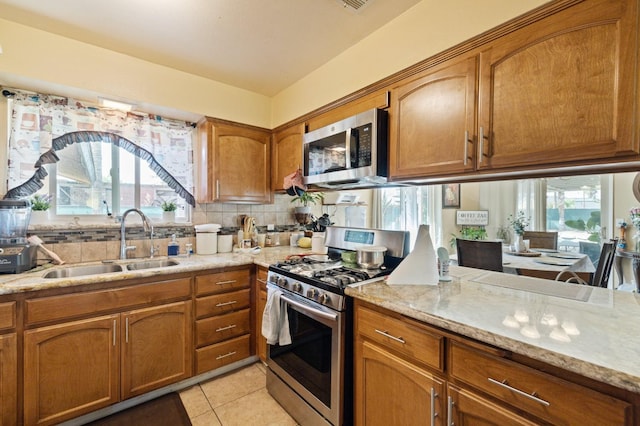 kitchen with tasteful backsplash, sink, light stone counters, stainless steel appliances, and light tile patterned floors