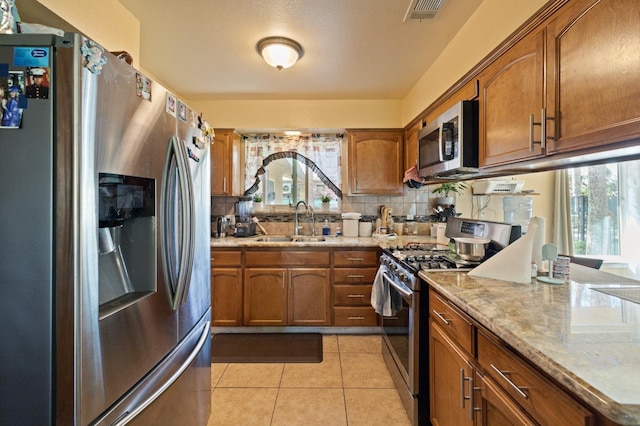 kitchen with appliances with stainless steel finishes, sink, decorative backsplash, and a healthy amount of sunlight