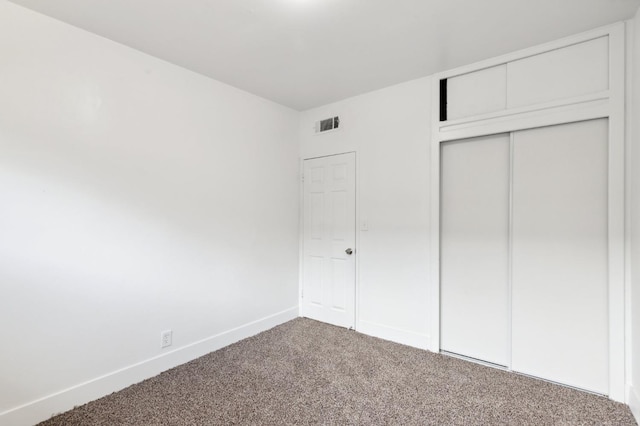 unfurnished bedroom with a closet, carpet flooring, visible vents, and baseboards