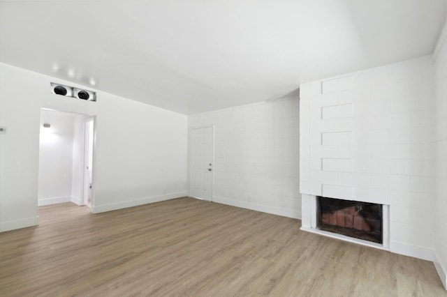 unfurnished living room with light wood-type flooring, baseboards, and a multi sided fireplace