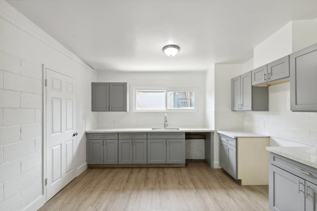 kitchen featuring light wood-style floors, light countertops, decorative backsplash, and gray cabinetry