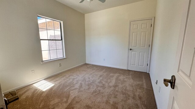 carpeted spare room with ceiling fan