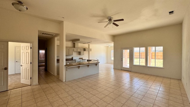 kitchen featuring ceiling fan, a breakfast bar, stainless steel range, and light tile patterned floors