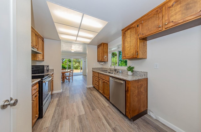 kitchen featuring light stone countertops, sink, stainless steel appliances, and light wood-type flooring