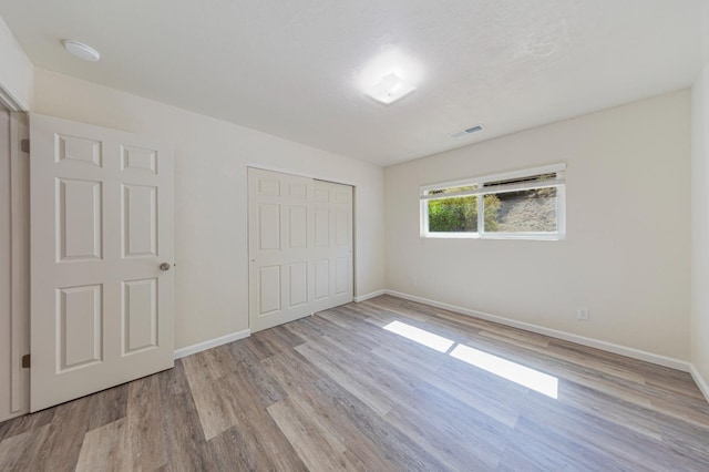 unfurnished bedroom featuring light wood-type flooring and a closet