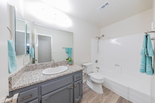 full bathroom with shower / tub combination, vanity, hardwood / wood-style flooring, and toilet