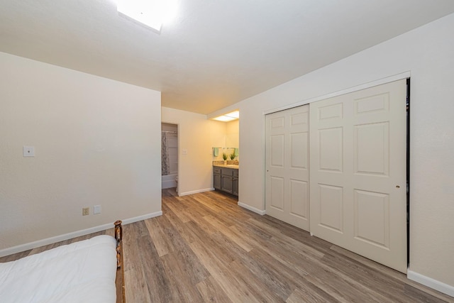 unfurnished bedroom with light wood-type flooring, ensuite bathroom, and a closet