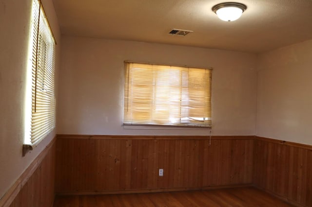 empty room with wood-type flooring and wooden walls