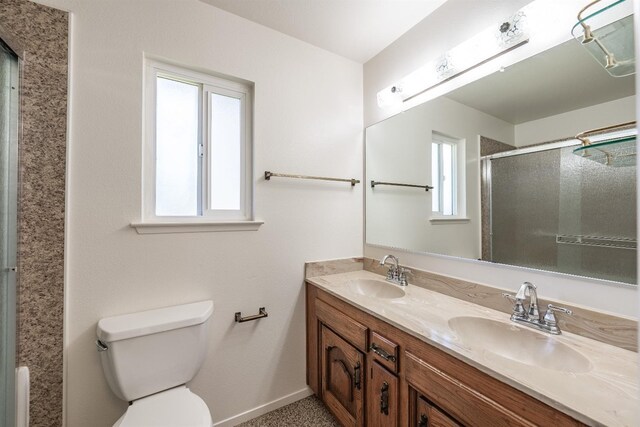 bathroom featuring plenty of natural light, a shower with door, vanity, and toilet