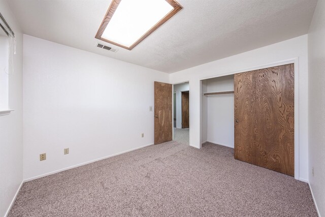 unfurnished bedroom with carpet, a closet, and a textured ceiling