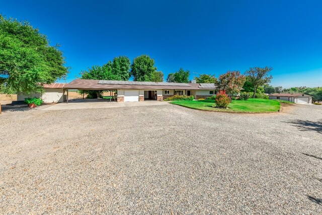 ranch-style home featuring a carport and a front yard