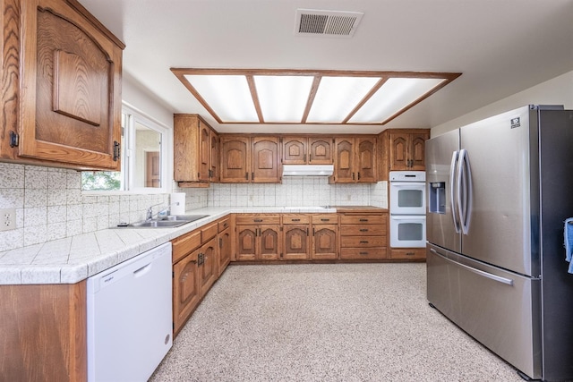 kitchen featuring sink, tasteful backsplash, and white appliances