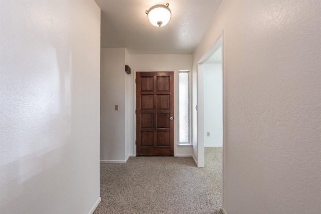 hall featuring carpet floors and a textured ceiling