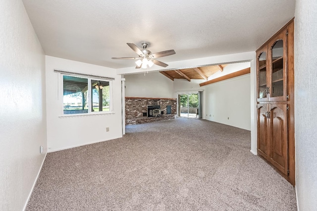 unfurnished living room with ceiling fan, vaulted ceiling with beams, carpet, and a fireplace